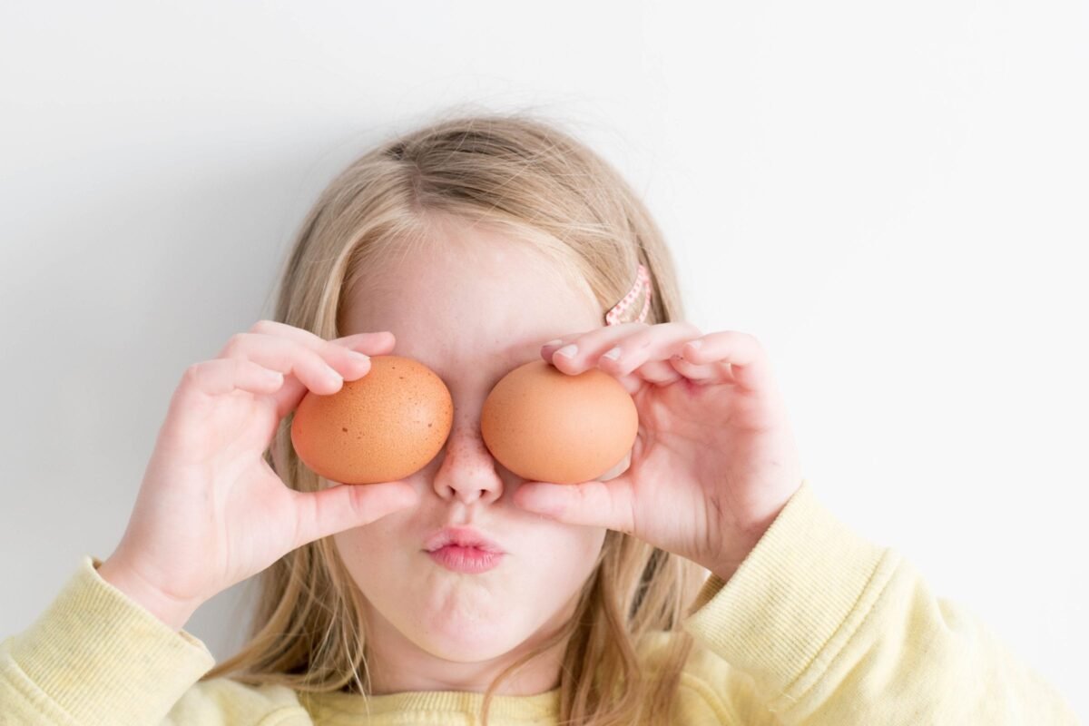 Little girl holding egg on her eyes